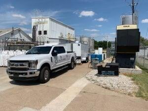 Alturex service truck and trailer beside an enclosed standby generator at a customer facility