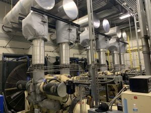 Indoor generator room with multiple engine-generator sets and overhead exhaust piping
